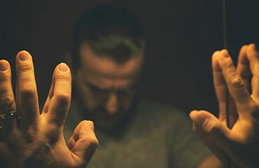 Man looking down with hands on mirror