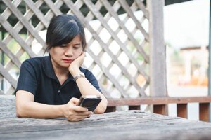 woman holding phone thinking about questions to ask anxiety helpline